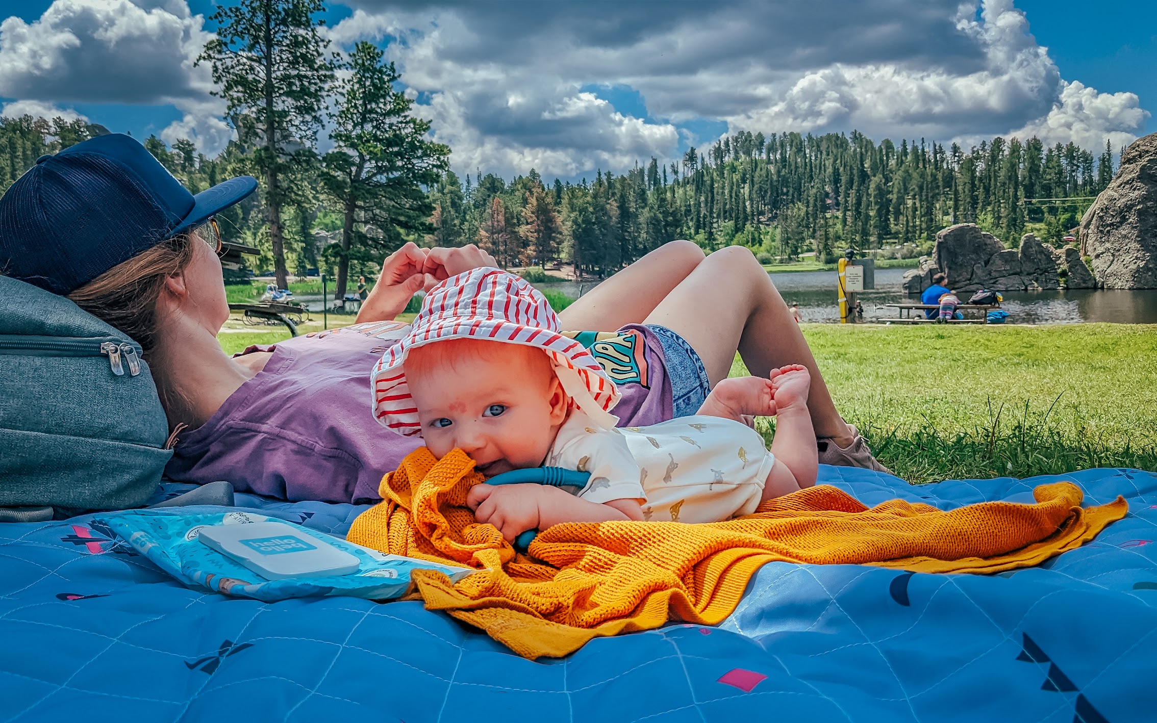 Baby resting on a picnic blanket beside a lake