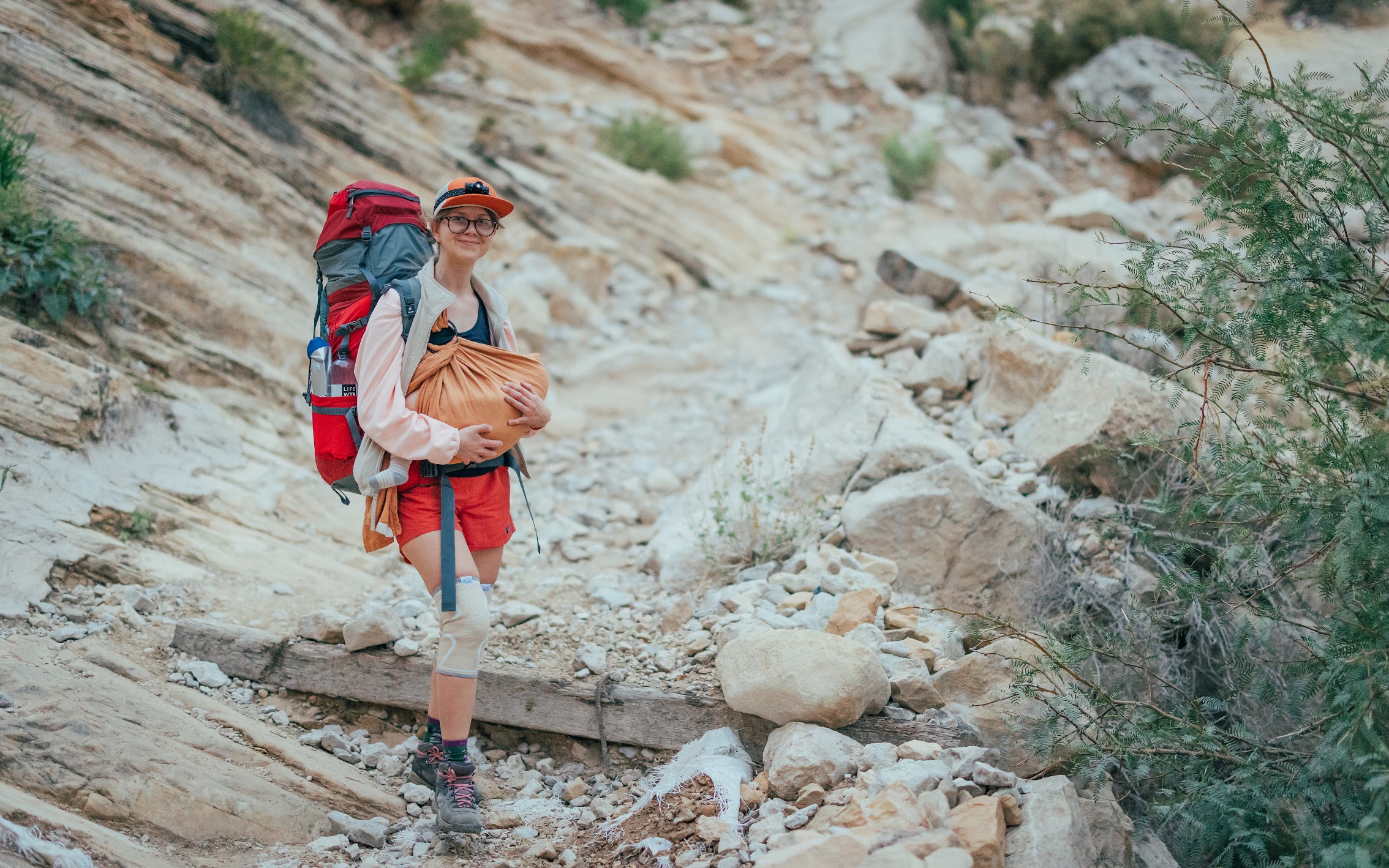 Ula hiking with a baby carrier in a canyon landscape