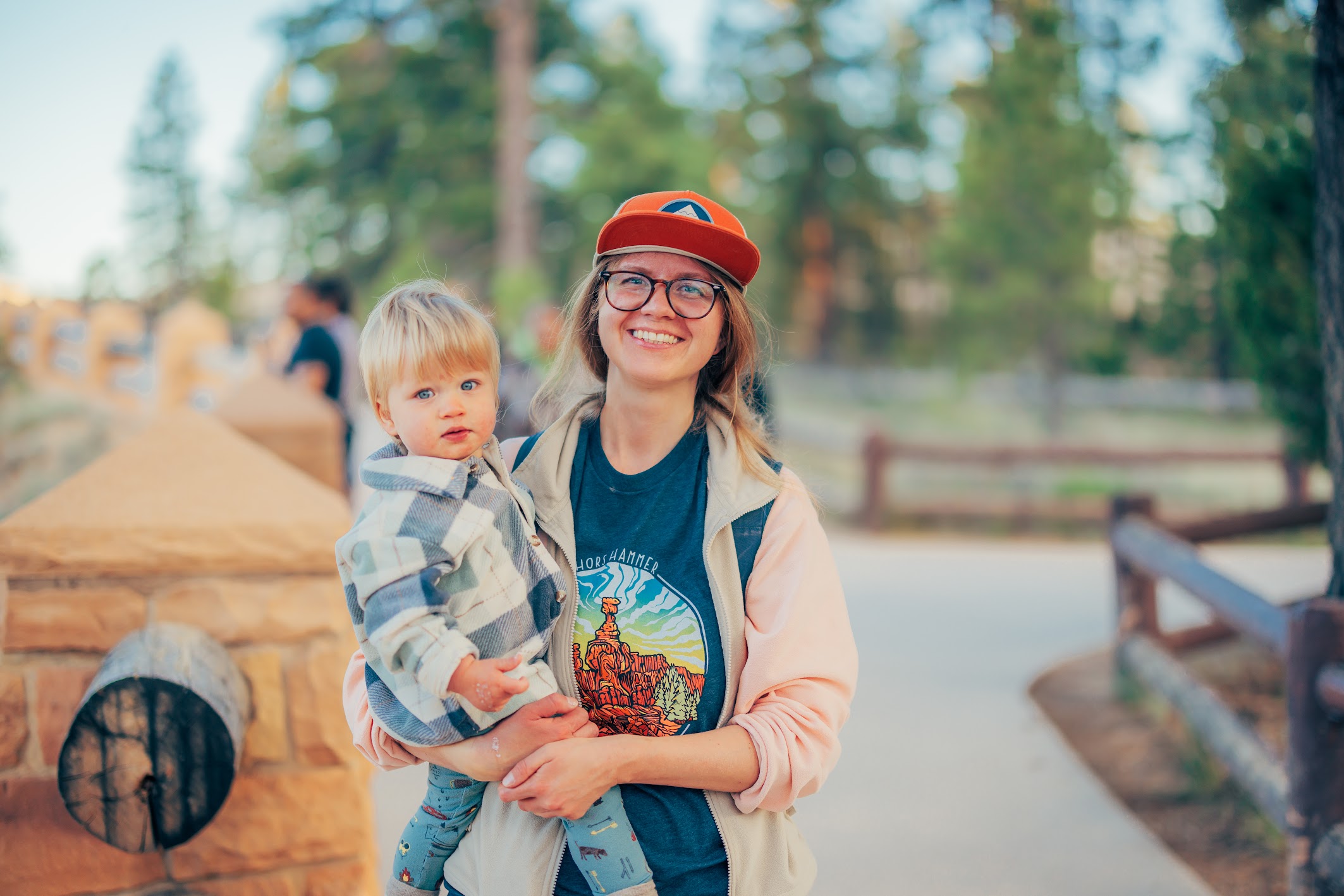 Ula holding a toddler and smiling outdoors